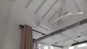 A modern hotel room with a ceiling fan, air conditioning unit, and sheer curtains. - White Villa (Tangalle)