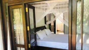 A room with a bed, a window with curtains, and a stone-tiled floor. - White Villa (Tangalle)