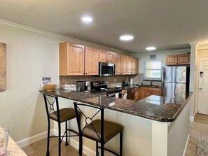 A kitchen with wooden cabinets, a granite countertop, and stainless steel appliances.