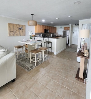 Una cocina moderna con una isla central, armarios de madera y un comedor con mesa y sillas blancas.
