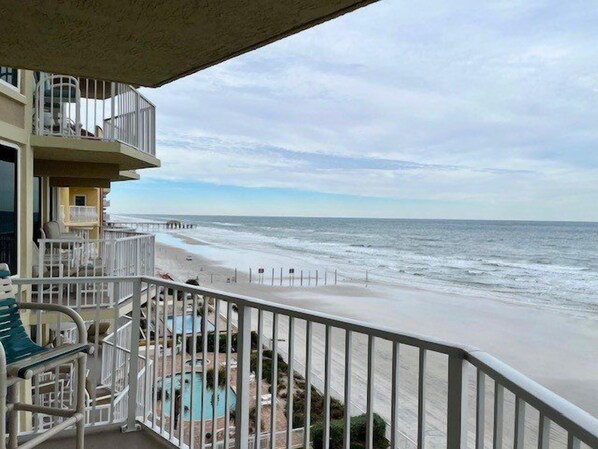 A balcony with a view of the beach and ocean.
