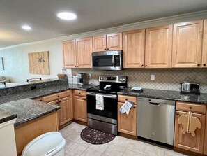A kitchen with wooden cabinets, stainless steel appliances, and a granite countertop.