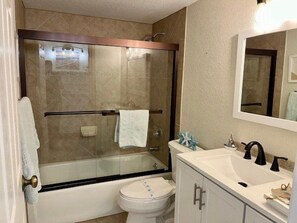 Une salle de bain moderne avec une douche à parois de verre, des toilettes blanches, un meuble-lavabo et un miroir.