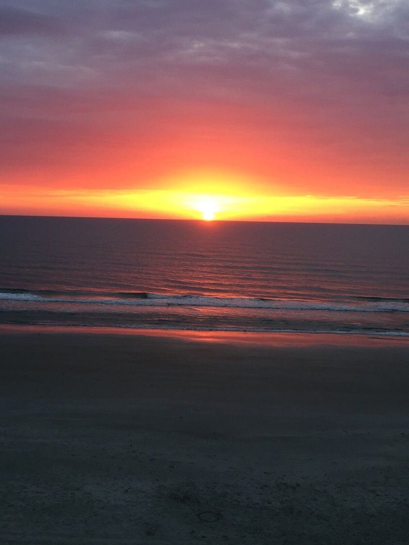 Un coucher de soleil sur une plage, avec des vagues.