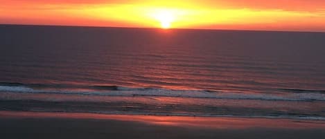 Un coucher de soleil sur une plage, avec des vagues.