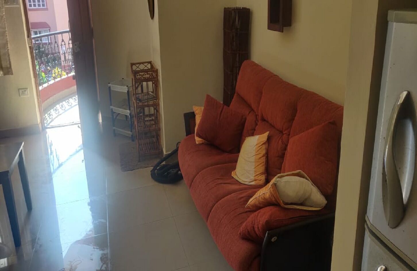 Un soggiorno con un divano rosso, una sedia di legno e una lavatrice.