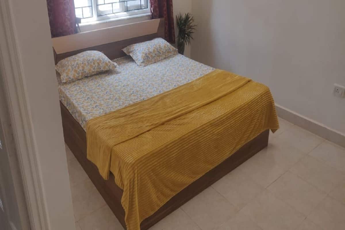 A bedroom with a bed, a window, and a plant.