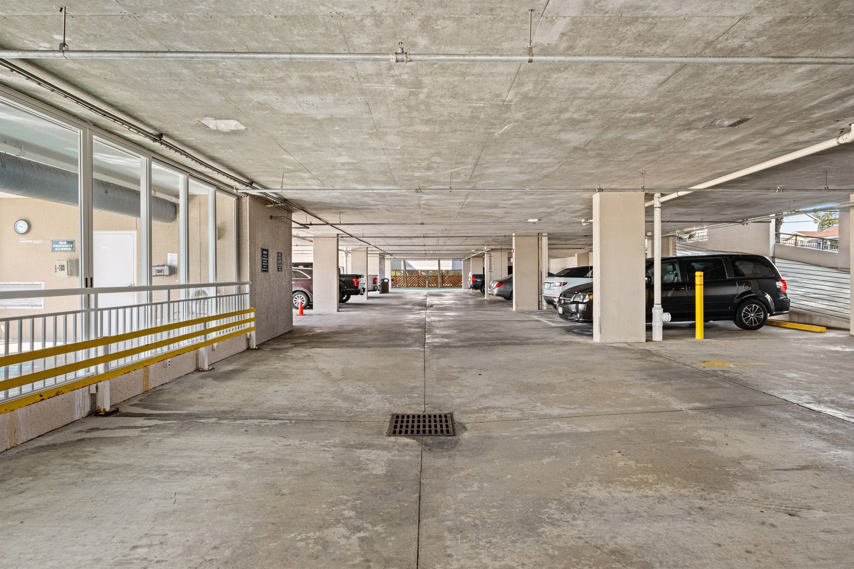 A multi-level parking garage with concrete floors and columns, clear signage, and a yellow safety line.