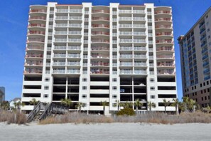 A multi-story hotel with balconies, a central staircase, and a beachside location.
