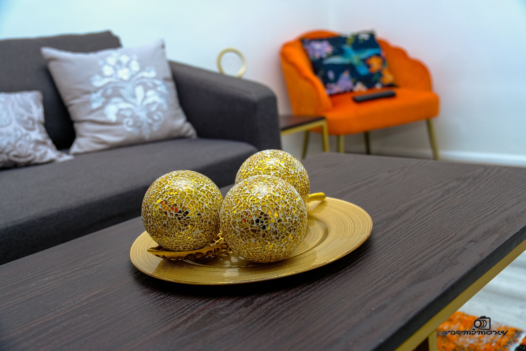 Uma sala de estar moderna com uma mesa de centro de madeira escura e esferas douradas decorativas.
