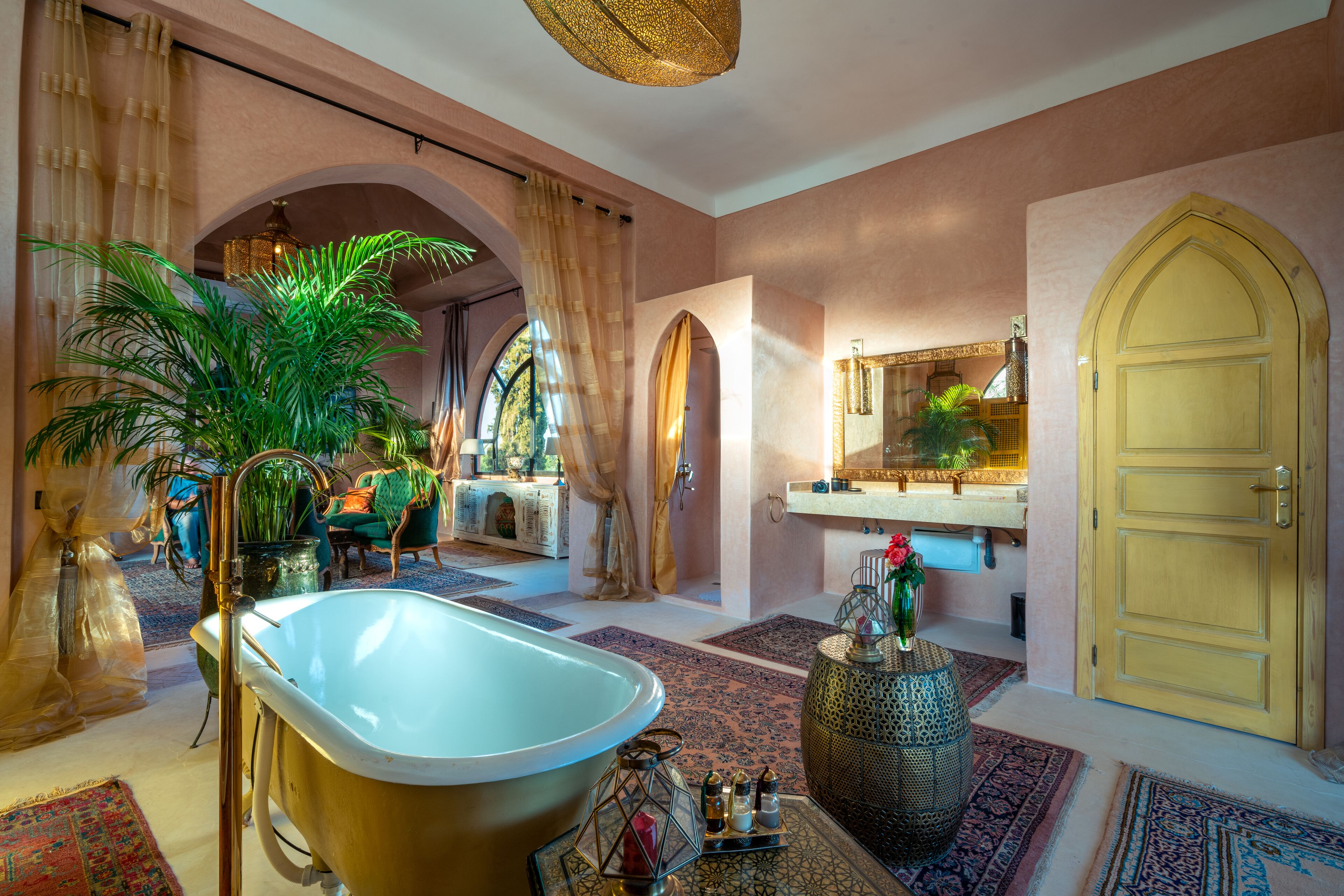 Un baño lujoso con una bañera independiente, un espejo grande y un jarrón decorativo.
