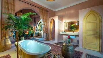 Un baño lujoso con una bañera independiente, un espejo grande y un jarrón decorativo.