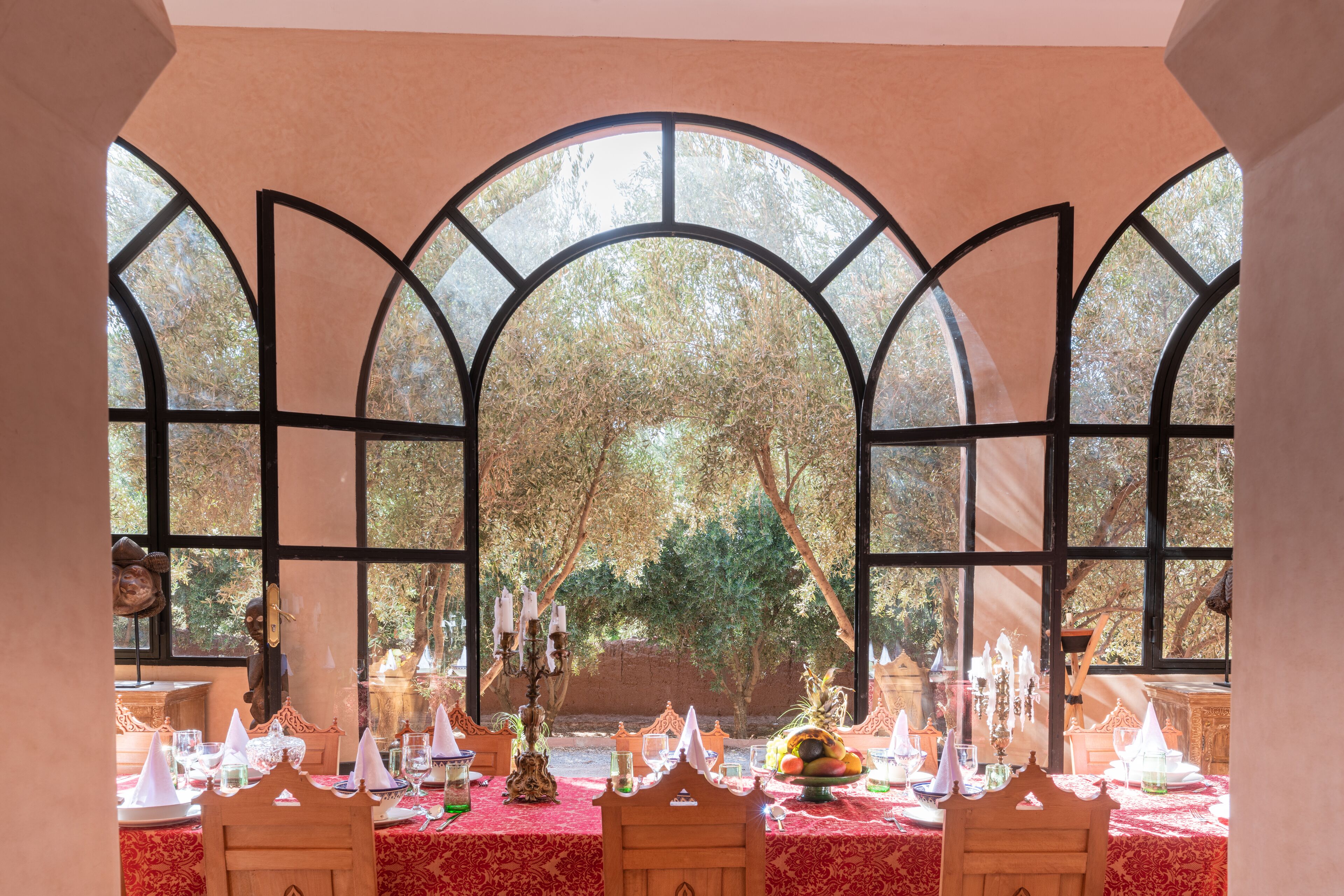 Una mesa de comedor decorada con manteles blancos, velas y un centro de mesa con frutas.