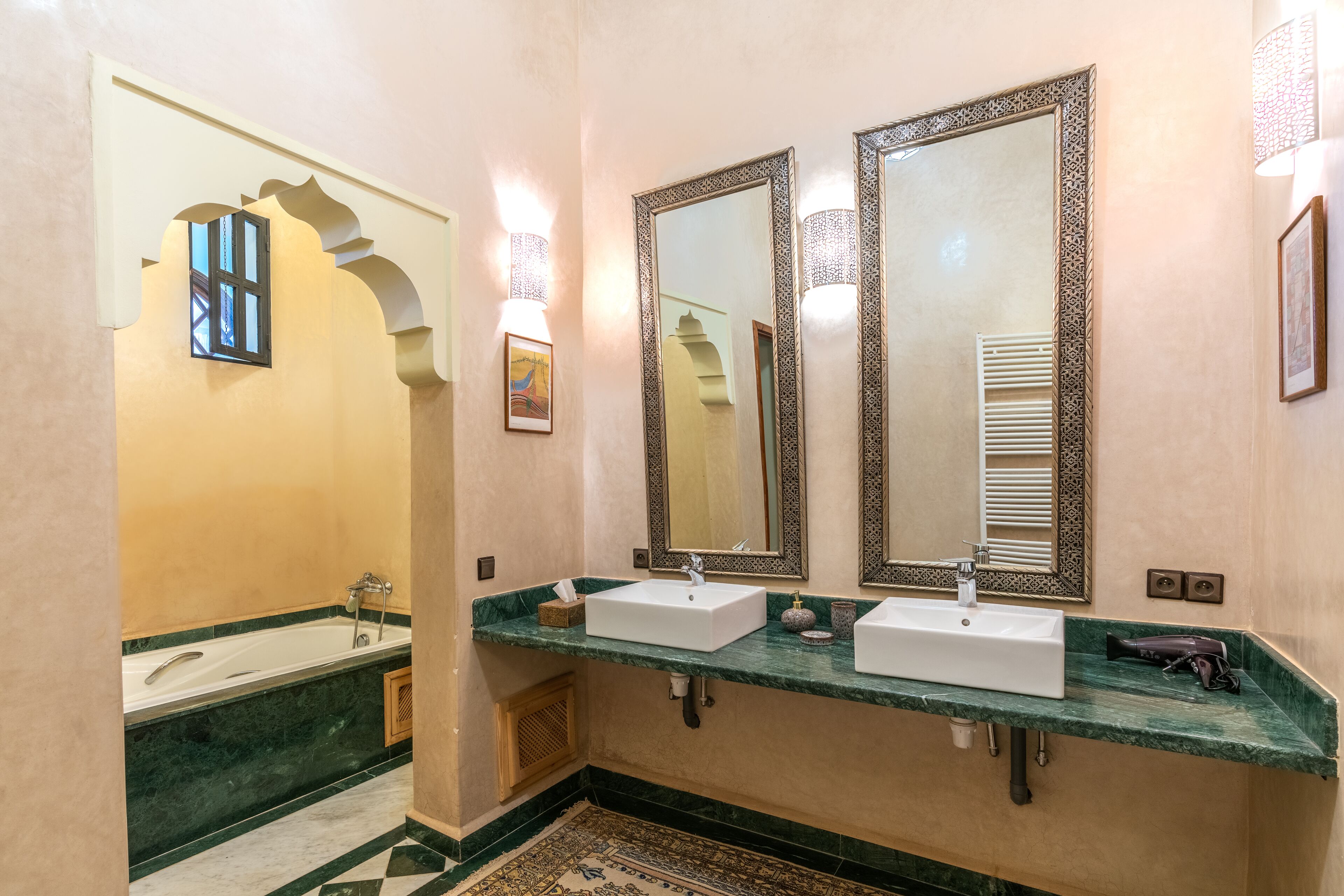 Un bagno con due lavandini, una vasca e un grande specchio con cornici decorative.