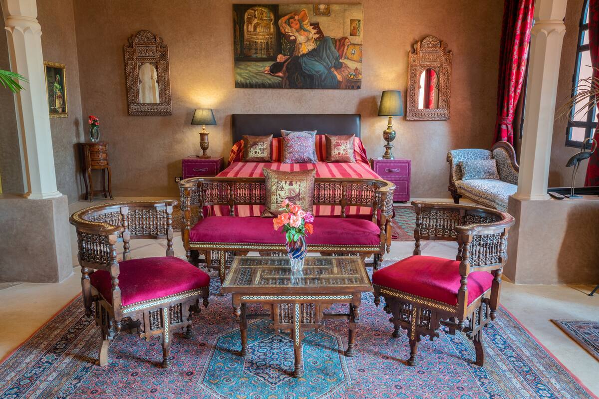 A traditional room with a bed, two chairs, a table, and a rug.