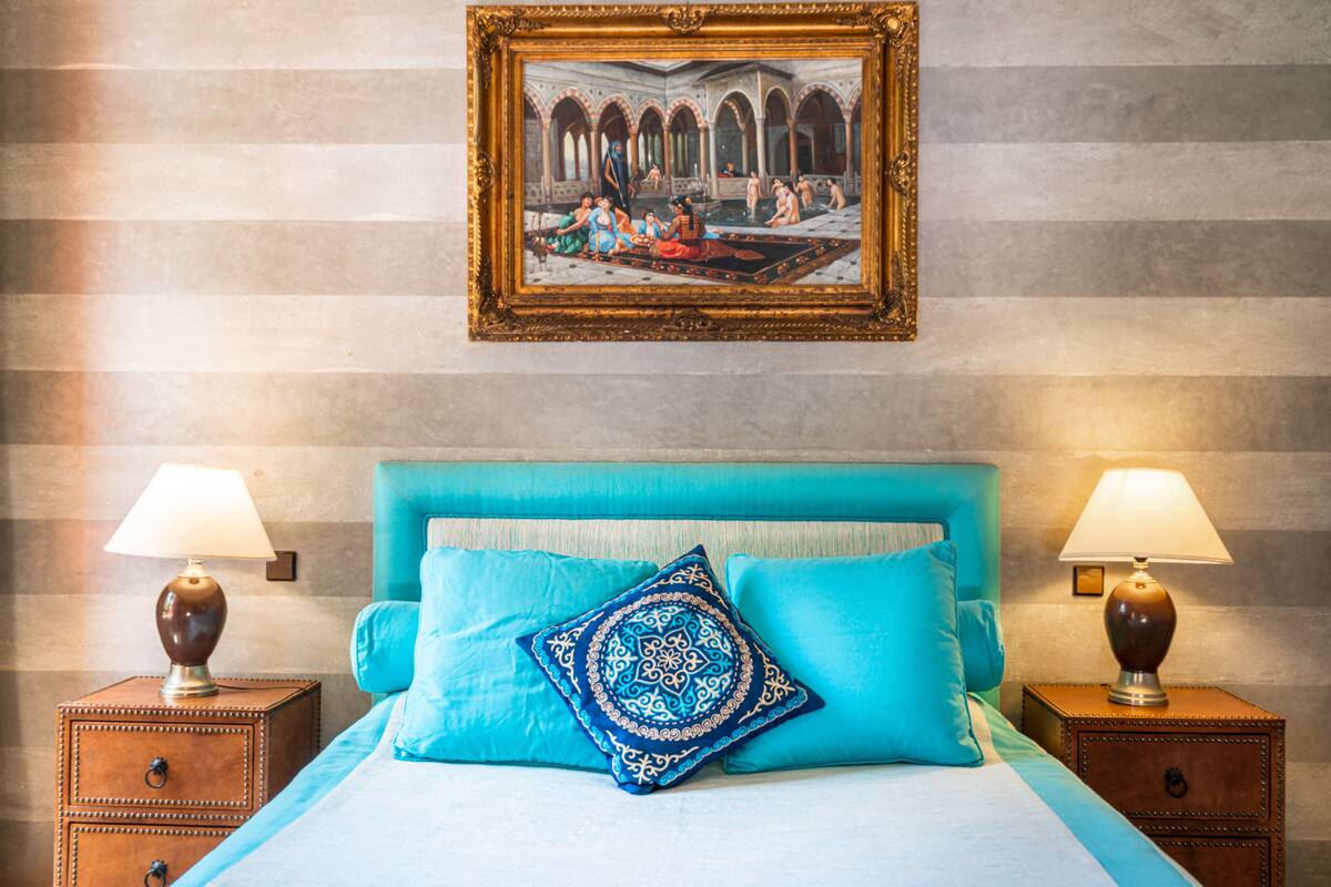 A hotel room with a large bed, two nightstands, two lamps, and a framed picture on the wall.