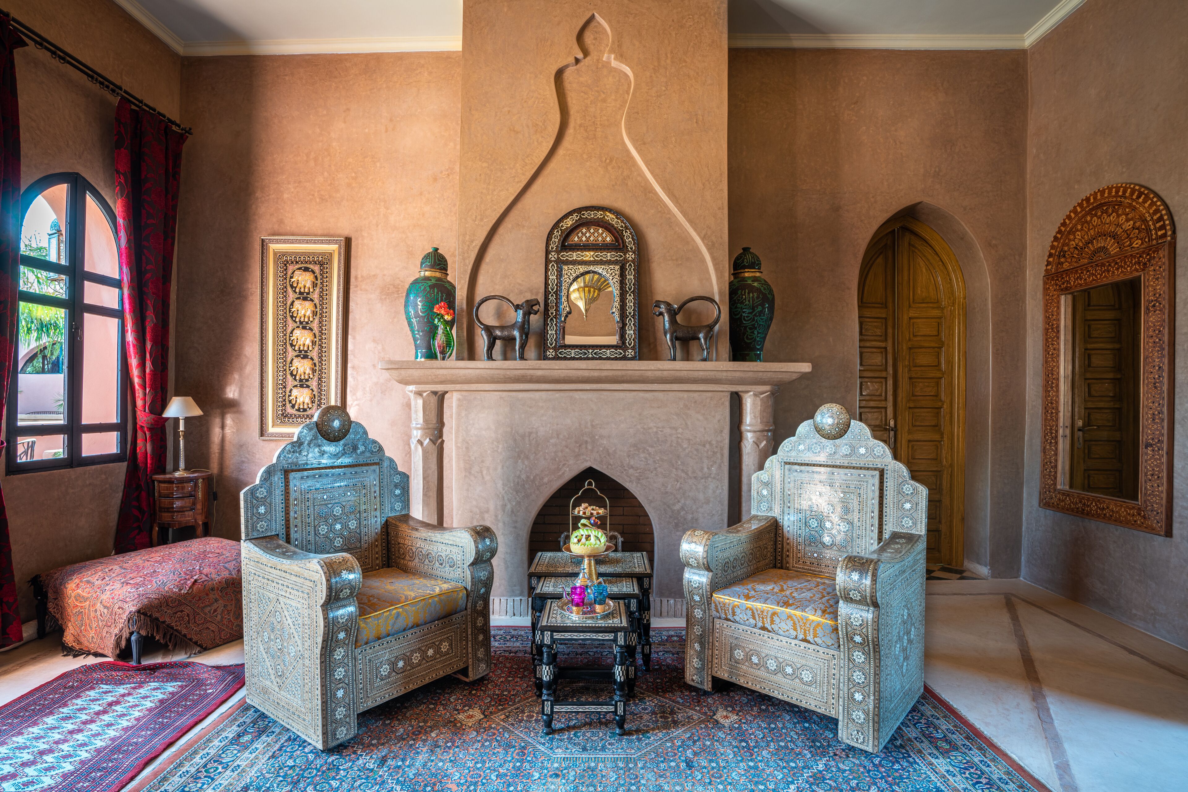 Una habitación tradicional con muebles ornamentados, chimenea y un espejo grande.