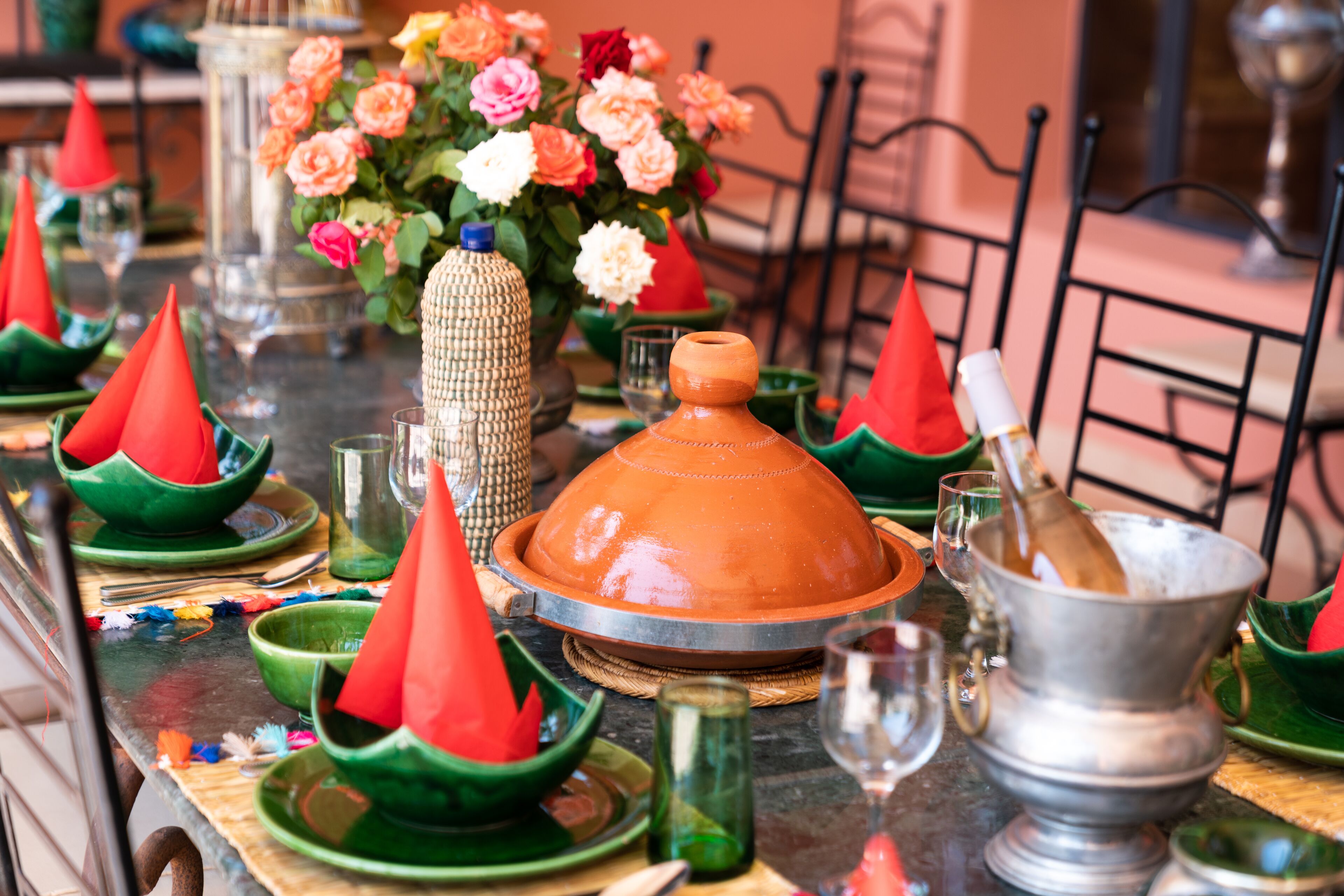Una mesa de comedor dispuesta con platos tradicionales marroquíes, incluyendo tajines y cocinas de barro, y una variedad de vajilla de colores.