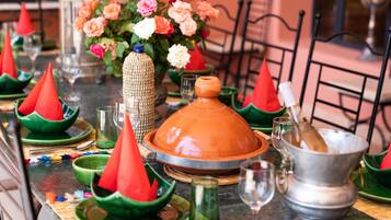 Una mesa de comedor dispuesta con platos tradicionales marroquíes, incluyendo tajines y cocinas de barro, y una variedad de vajilla de colores.