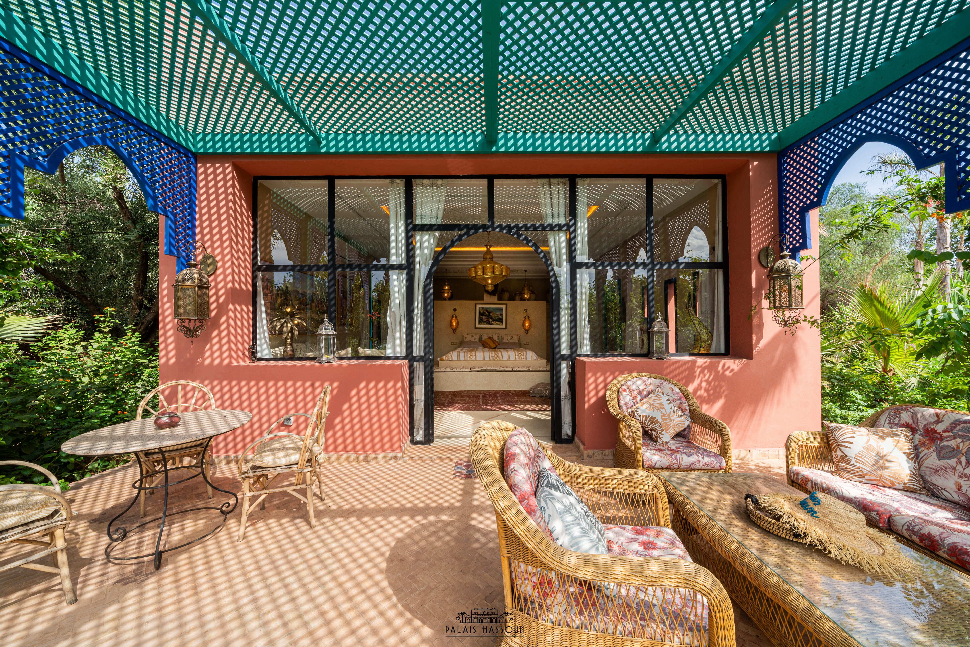 An outdoor seating area with wicker furniture, a table, and a view of the interior through large windows.