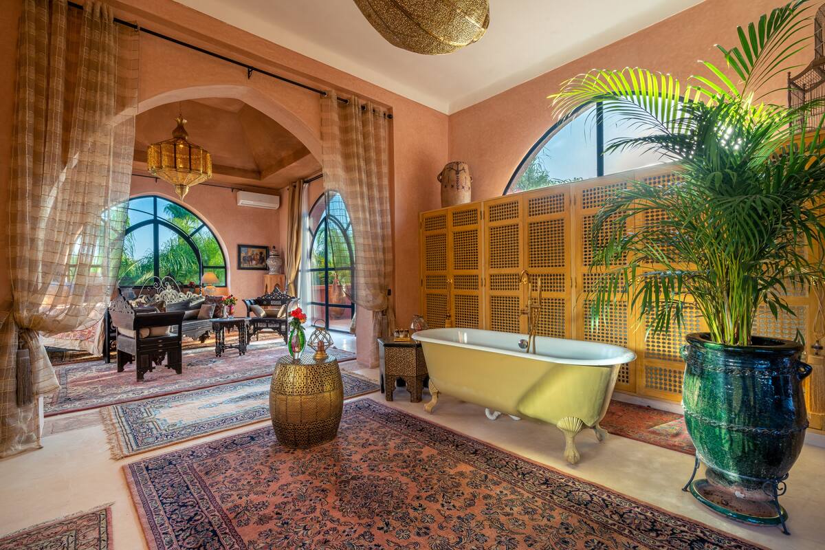 A spacious bathroom with a freestanding bathtub, large windows, and a tropical plant.