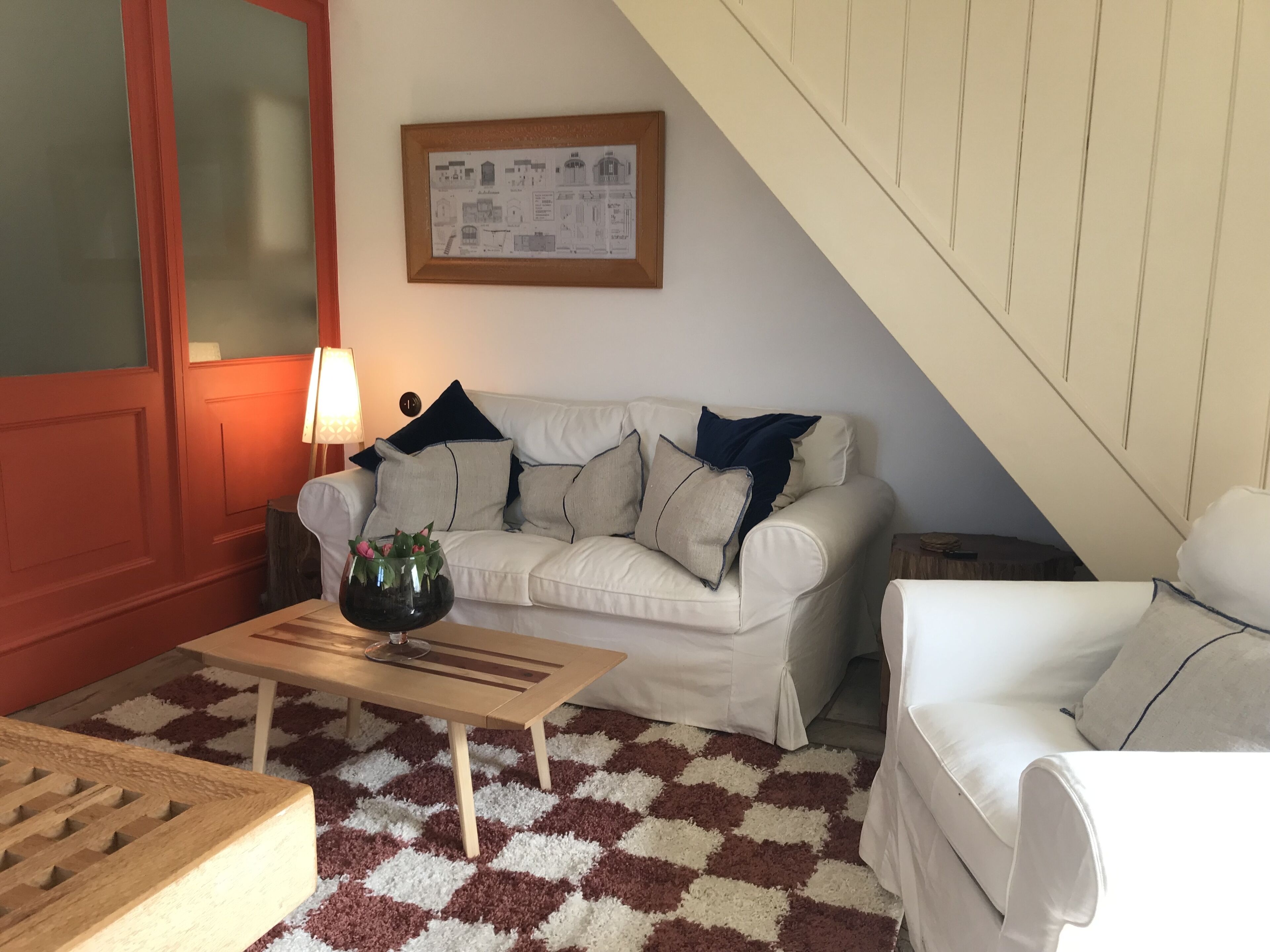 Una sala de estar acogedora con un sofá blanco, una mesa de centro de madera y un tapete estampado.
