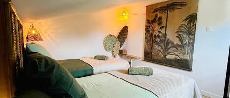 A room with two beds, a large painting, and a wall-mounted light fixture.