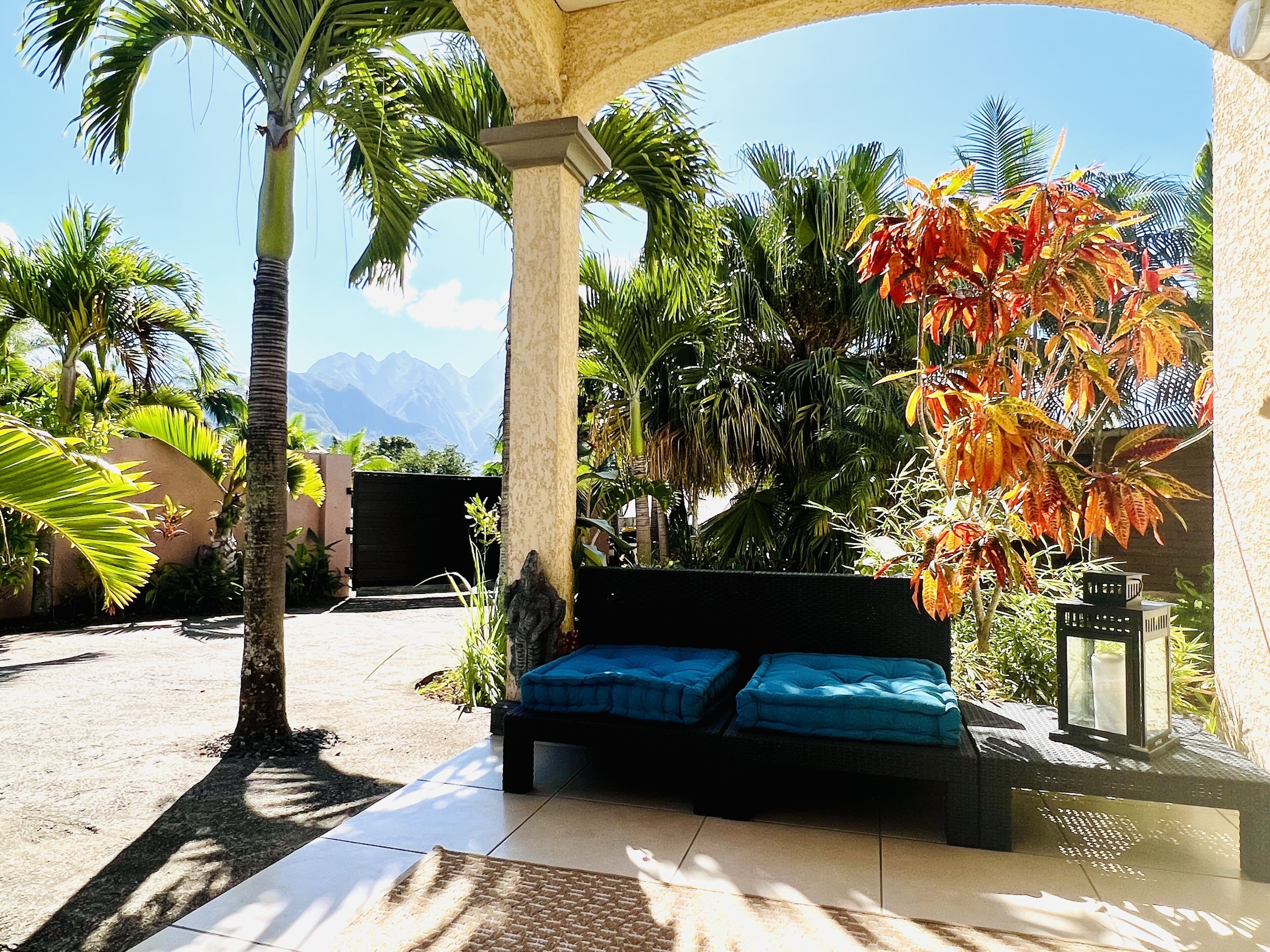 Eine Terrasse mit einer Sitzecke, Palmen und Blick auf die Berge.