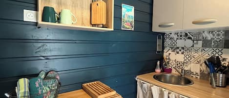 A kitchen with a wooden countertop, a sink, and a backsplash with patterned tiles.