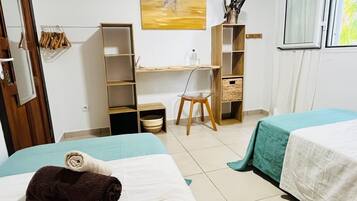 Una habitación de hotel con dos camas, un escritorio, una silla y un armario.