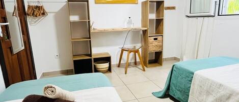 A hotel room with two beds, a desk, a chair, and a wardrobe.