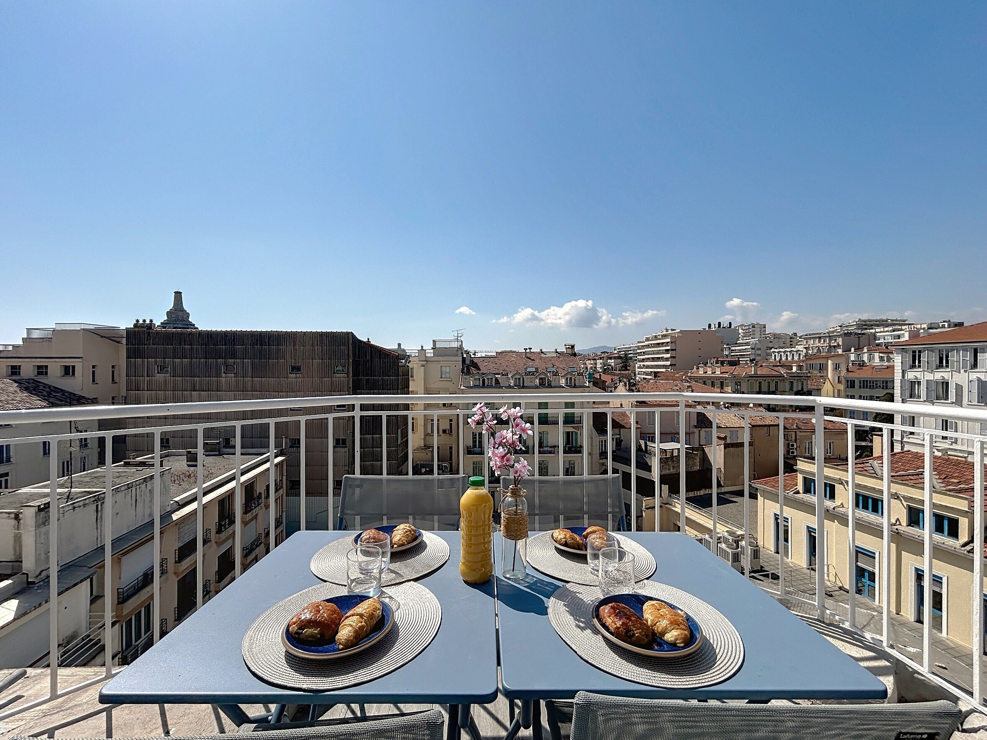 Eine Dachterrasse mit zwei Essplätzen mit Blick auf die Stadtlandschaft.