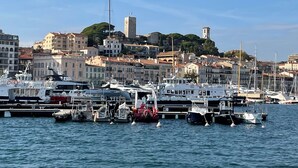 A marina with boats docked, surrounded by buildings and a hill with a tower. - 2 bedrooms with terrace 1 minute from the Palais Cannes Croisette Apartment (Cannes)