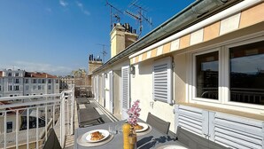 A balcony with a table set for breakfast, including croissants and a vase with flowers. - 2 bedrooms with terrace 1 minute from the Palais Cannes Croisette Apartment (Cannes)
