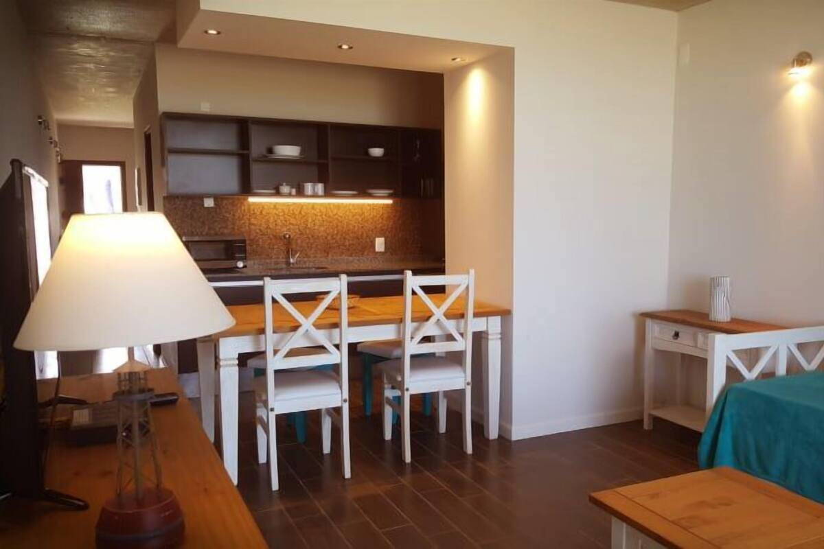 Een kleine woonruimte met een kitchenette, een eethoek en een bed.
