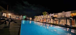 A nighttime view of a hotel with a swimming pool, outdoor seating, and well-lit buildings. - THE BEACH La Paloma  (La Paloma)