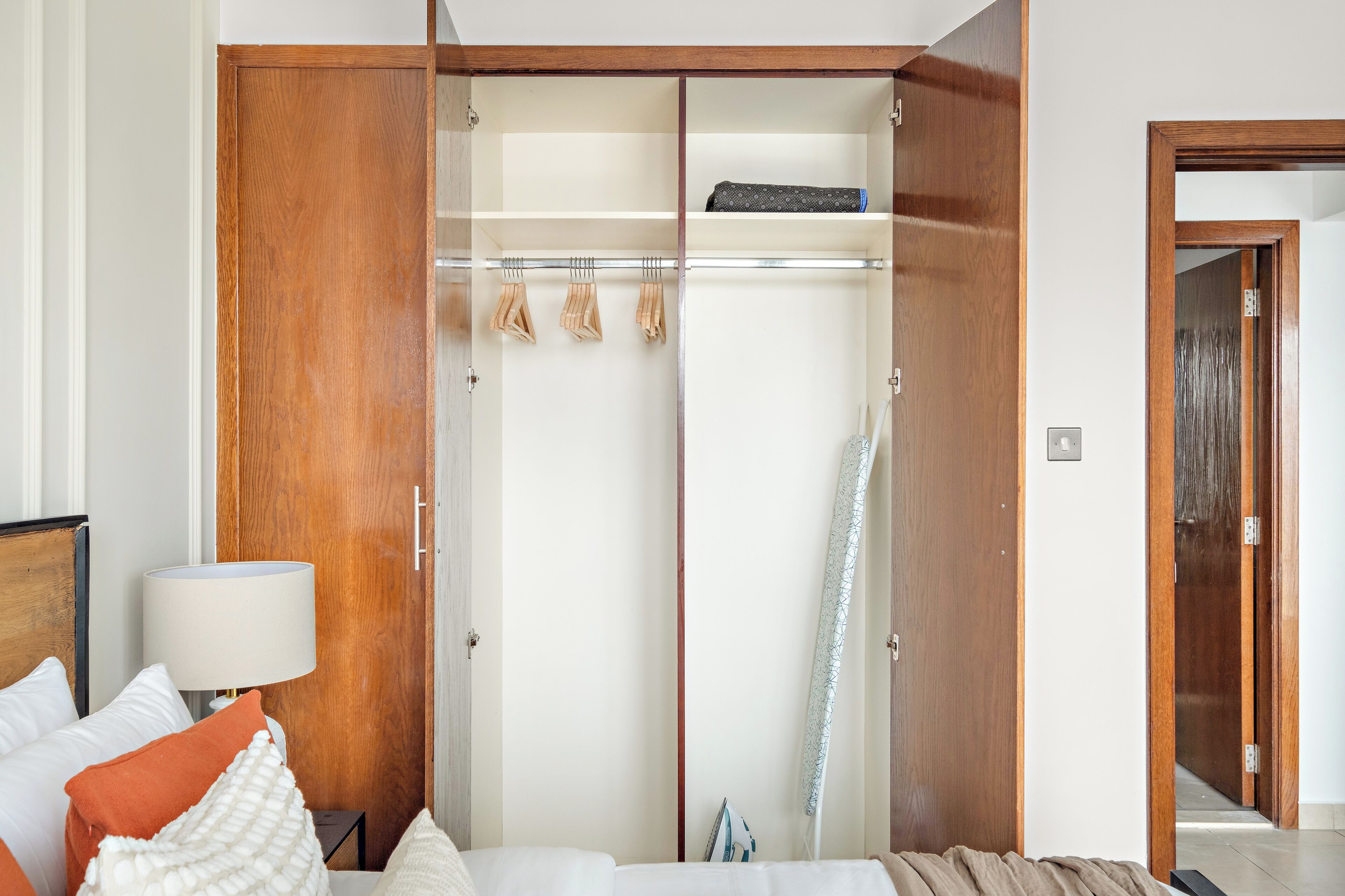 Ein Schlafzimmer mit einem Holzschrank, einem Bett mit weißer Bettwäsche und einem Nachttisch mit einer Lampe.