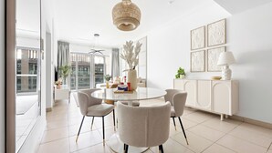 A modern dining area with a round table, four chairs, a decorative vase, and a white cabinet with artwork. - Silkhaus - 8 BLVD Walk (Dubai)