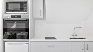A modern kitchen with a built-in microwave, oven, and sink. - Phaedrus Living: Alkminis Seaview Suites Pantai (Paphos)