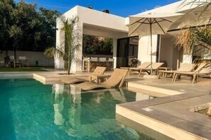 A modern outdoor pool area with lounge chairs and a covered seating area.