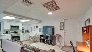 A modern living room with a leather sofa, a dining area with a wooden table, and a kitchen with white cabinets and appliances. - Tucson Studio ~ 2 Mi to University of Arizona! (Tucson)