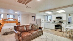 A spacious living area with a leather sofa, a dining table, and a kitchen with white cabinets and appliances. - Tucson Studio ~ 2 Mi to University of Arizona! (Tucson)
