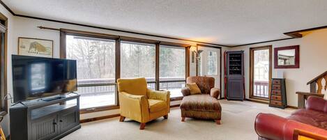 A living room with a television, two armchairs, a sofa, and a cabinet.