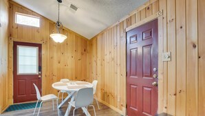 A wooden-paneled room with a dining table and chairs, a red door, and a ceiling light fixture. - Round Rock Home With Large Yard: 20 Mi to Austin! (Round Rock)