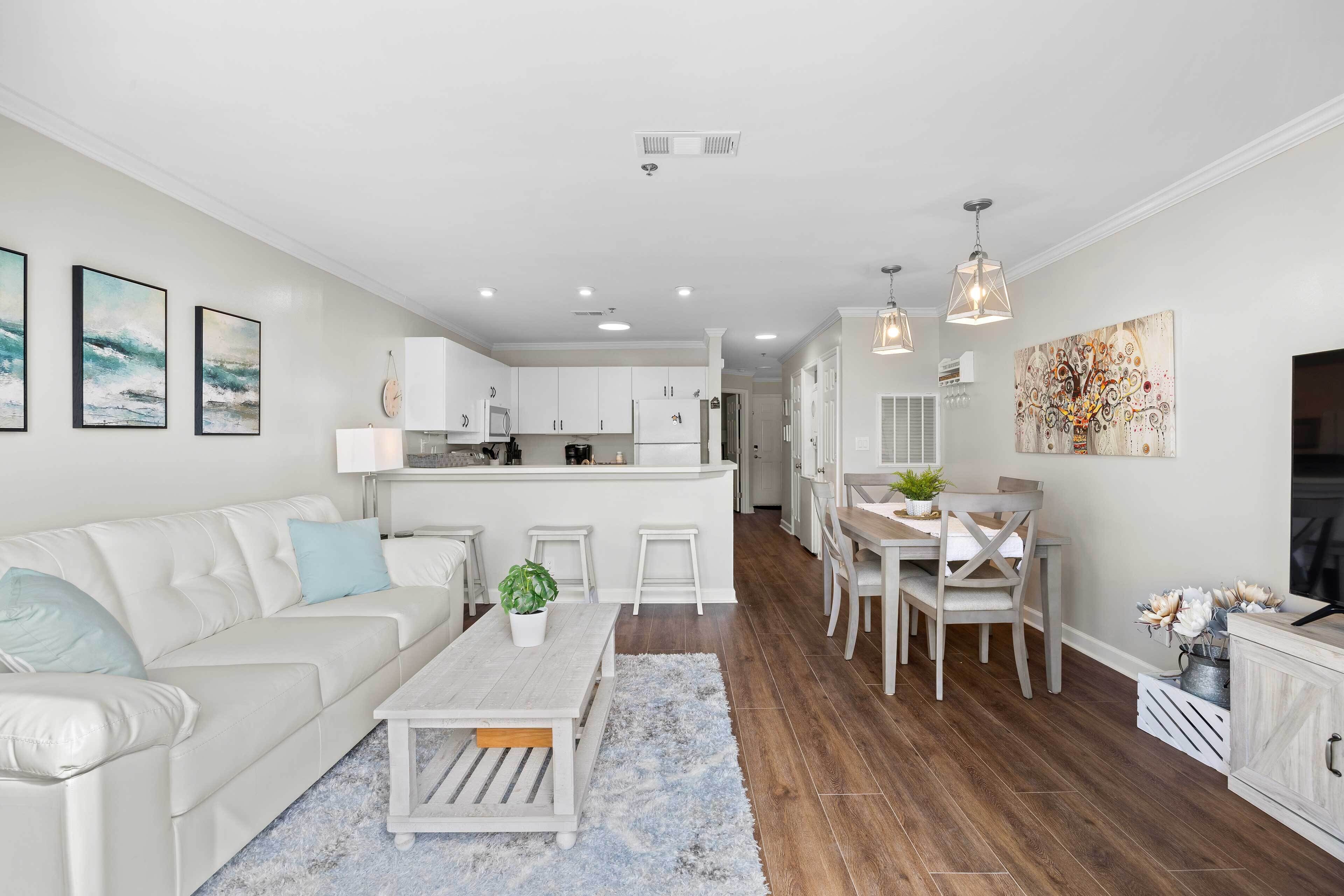 A modern kitchen with white cabinets, a central island, and pendant lighting.