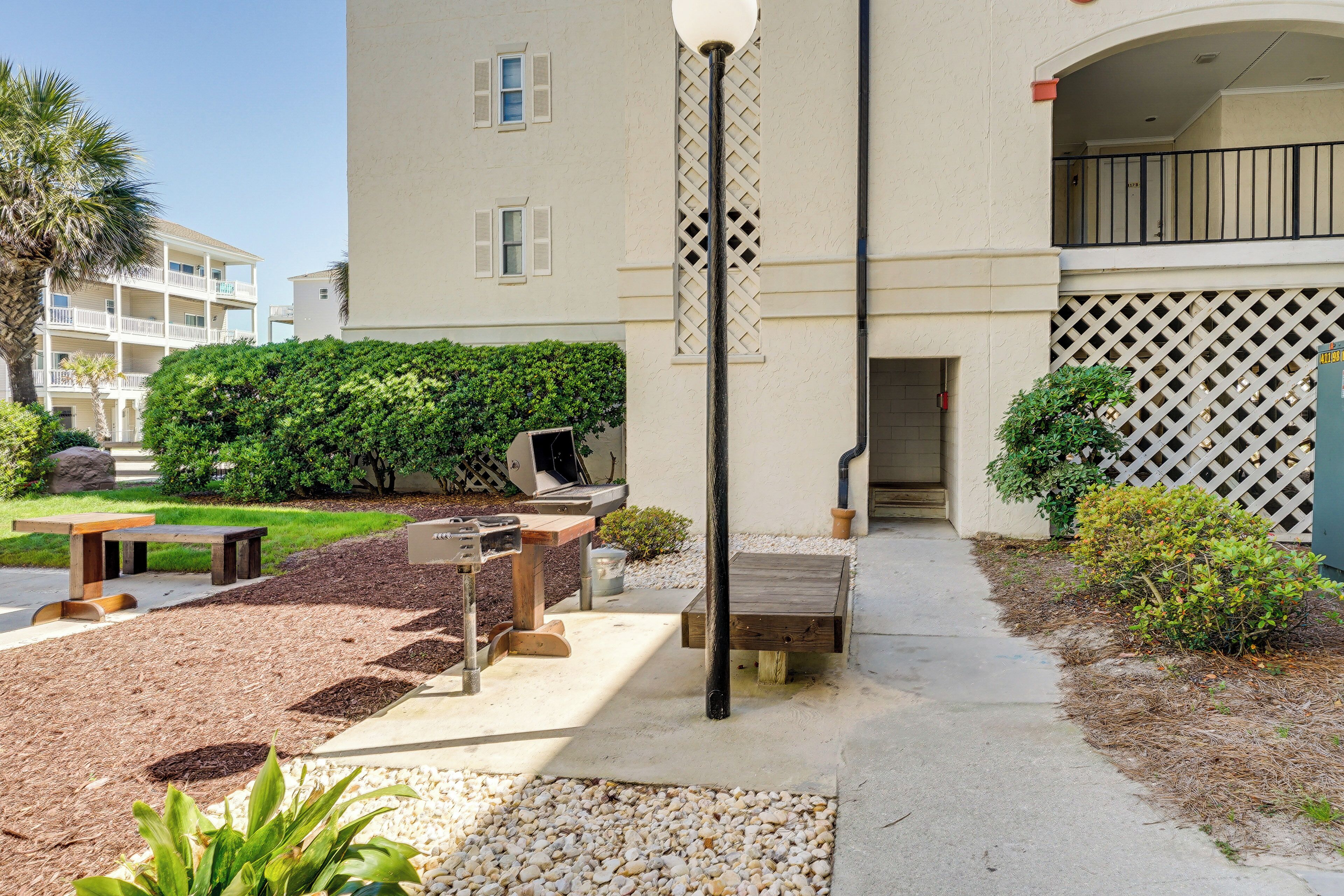 A courtyard with a wooden bench, a small table, and a planter with green plants.