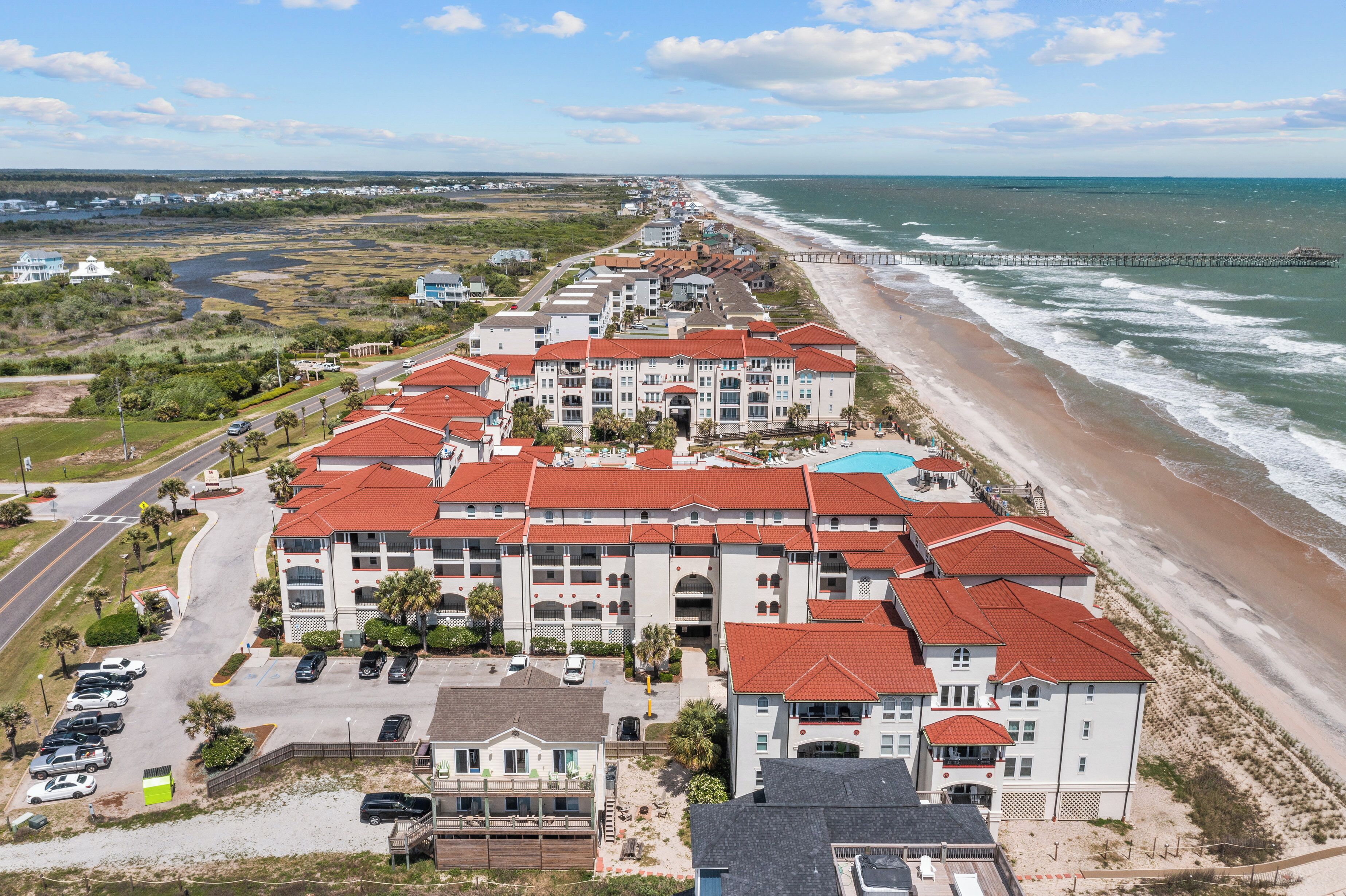 Ein Strandhotel mit mehreren Gebäuden, einem Parkplatz und Blick auf den Strand.