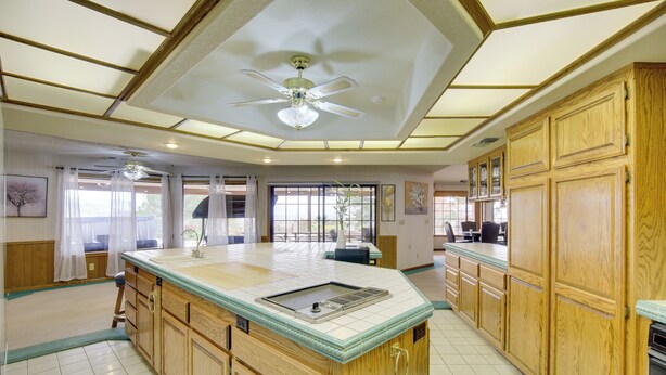 Un'ampia cucina con mobili in legno, un'isola centrale e una ventola a soffitto.