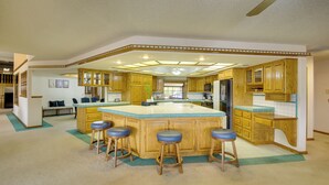 Un'ampia cucina con un'isola grande, mobili in legno e sgabelli da bar.
