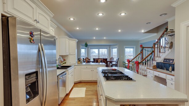 A spacious kitchen with white cabinetry, a stainless steel refrigerator, a central island, and a wooden staircase. - 6 Mi to Bourbon Trail: Group Estate on 20 Acres (Shelbyville)